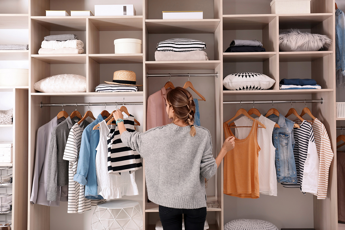 Young woman infront of open wardrobe choosing clothes