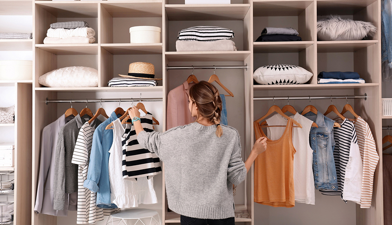 Young woman infront of open wardrobe choosing clothes