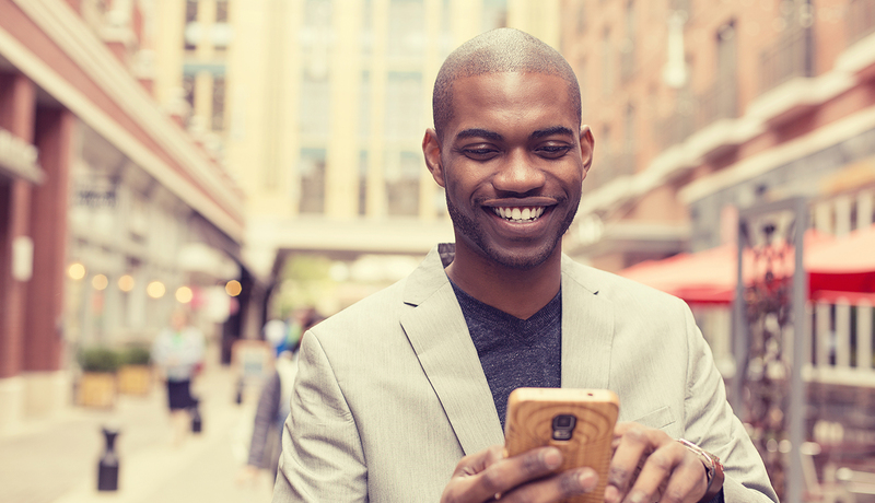 Happy man on phone walking down a street