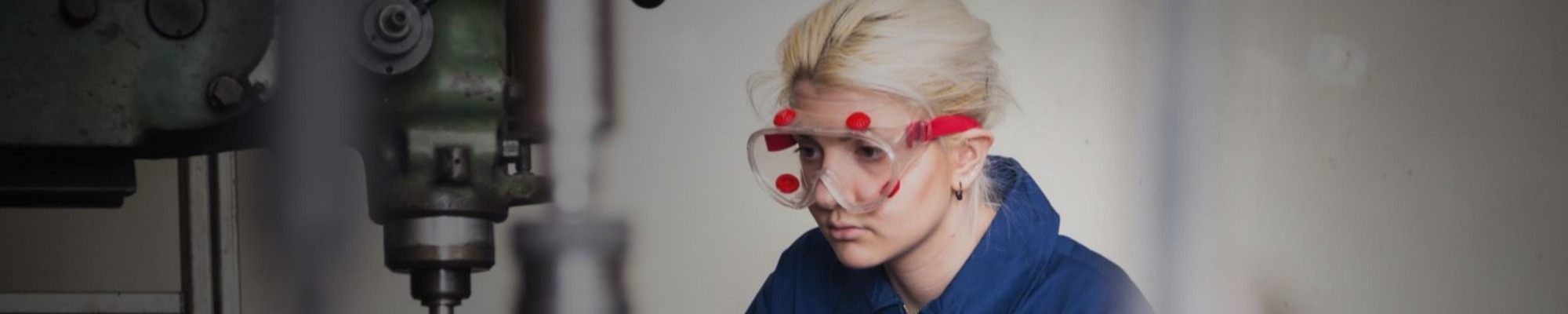 Young woman working on machine wearing personal protective equipment